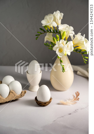 Spring, Easter background. White freesias flowers in a vase with white eggs. Spring, Easter background. White freesias flowers in a vase with white eggs. 134424353