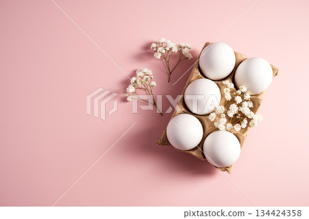 Easter holiday background. White eggs and white spring Gypsophila flowers in carton box on pastel pink background. Easter holiday background. White eggs and white spring Gypsophila flowers in carton box on pastel pink background. 134424358
