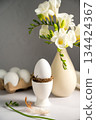 Spring, Easter background. White freesias flowers in a vase with white eggs. 134424367