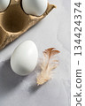 Easter, spring background. White chicken eggs in egg carton box with feather 134424374