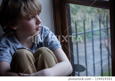 Sad Depressed Boy Young Male Child Looking Out of a Window Sad Depressed Boy Young Male Child Looking Out of a Window 134424381