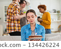 Sad lonely frustrated unhappy young woman looking at birthday cake with candle on birthday party. Girl sad disappointed thinking about life. Birthday party with friends. People celebrating birthday 134426224