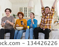 Home party. Cheerful group of friends playing video games at home. Happy diverse group buddies having fun together indoor. Friendship leisure entertainment concept. Young best friends enjoying weekend 134426226