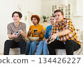 Home party. Cheerful group of friends playing video games at home. Happy diverse group buddies having fun together indoor. Friendship leisure entertainment concept. Young best friends enjoying weekend 134426227