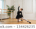 Young ballerina in tutu skirt dancing practicing ballet positions in dance class. Young classical dancer woman in dance studio. Ballet class training. Performer girl rehearsing dance in ballet school 134426235