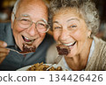 Happy elderly couple enjoying dessert together with joyful expressions 134426426