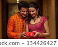 Couple in traditional attire exchanging gift box with joyful expressions 134426427