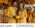 Joyful couple exchanging gift during festive celebration in vibrant attire 134426432