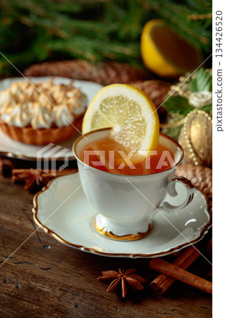 White cup of tea with lemon and meringue tartlet. 134426520