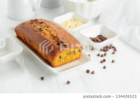 Cake with chocolate pieces on a white table. Cake with chocolate pieces on a white table. 134426523