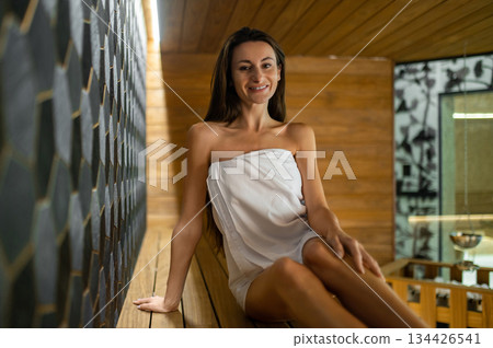 Cute young caucasian woman sitting on a bench in sauna 134426541