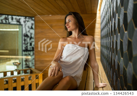 Cute young caucasian woman sitting on a bench in sauna 134426543