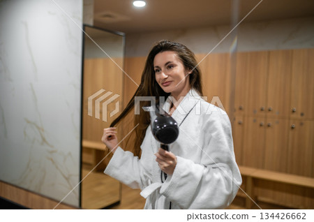 Long-haired caucasian young woman in white robe drying her hair 134426662