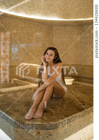 Pretty young woman in white towel on a massage table in a spa center Pretty young woman in white towel on a massage table in a spa center 134426688