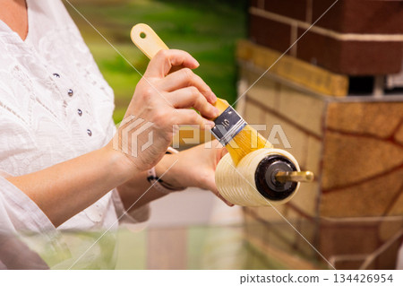 Woman painting with brush on decorative roller in artistic workspace Woman painting with brush on decorative roller in artistic workspace 134426954