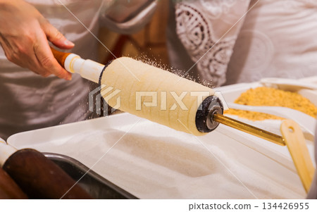 Hand rolling pastry dough with traditional tool in culinary setting Hand rolling pastry dough with traditional tool in culinary setting 134426955