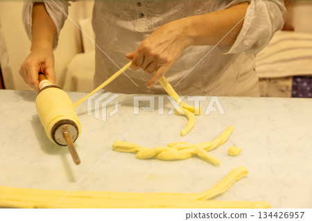 Woman preparing traditional dough with rolling pin on kitchen countertop Woman preparing traditional dough with rolling pin on kitchen countertop 134426957