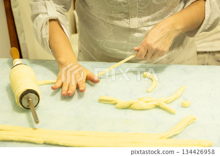 Woman shaping dough with rolling pin on kitchen countertop for baking Woman shaping dough with rolling pin on kitchen countertop for baking 134426958