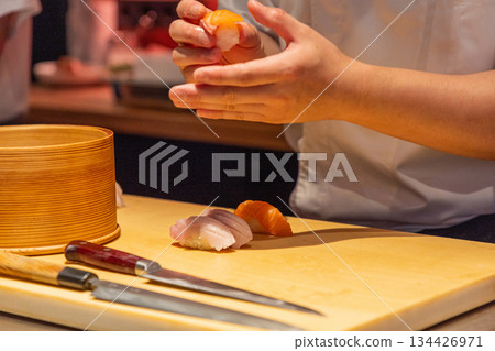 Sushi chef preparing fresh sushi rolls with precision and skillful hands Sushi chef preparing fresh sushi rolls with precision and skillful hands 134426971
