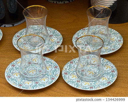 Turkish tea glasses with saucers arranged in set. Tea drinking ritual, traditional tableware, cultural hospitality, decorative patterns and everyday dining aesthetics Turkish tea glasses with saucers arranged in set. Tea drinking ritual, traditional tableware, cultural hospitality, decorative patterns and everyday dining aesthetics 134426999