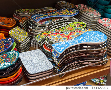 Hand painted Turkish ceramic spoon rests stacked on wooden shelf. Kitchen accessory design, functional decor, traditional craftsmanship, artisan pottery, culinary organization and decorative household 134427007