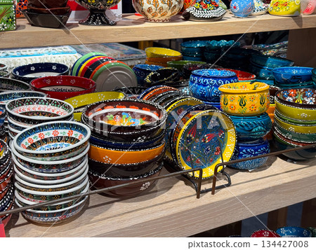 Decorative Turkish ceramic bowls and plates displayed in artisan shop. Traditional pottery, functional design, cultural craftsmanship, colorful tableware, handmade production and everyday domestic 134427008