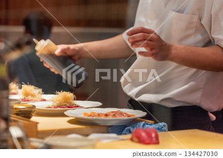 Chef preparing gourmet dishes with precision in a modern kitchen setting Chef preparing gourmet dishes with precision in a modern kitchen setting 134427030