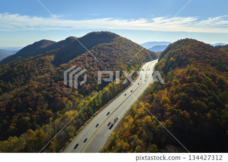 I-40 freeway road leading to Asheville in North Carolina thru Appalachian mountains with yellow fall forest and fast moving trucks and cars. Concept of high speed interstate transportation 134427312