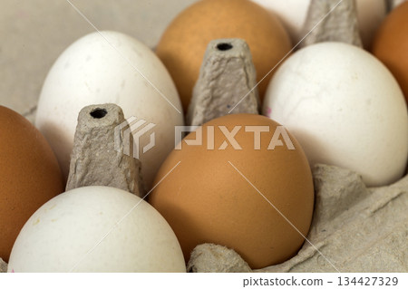 Hen eggs in open cardboard egg carton on kitchen table light copy space background. Healthy organic food and diet concept. Hen eggs in open cardboard egg carton on kitchen table light copy space background. Healthy organic food and diet concept. 134427329