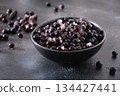 Frozen aronia or chokeberry berries with ice crystals in black bowl on dark stone background, healthy superfood ingredient concept. Raw food 134427441