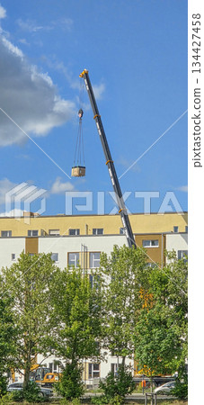 Berlin, Germany - May 05, 2025: Crane lifting construction materials above building under blue sky 134427458