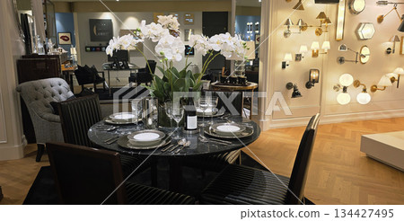 Berlin, Germany - September 19, 2025: Elegant dining room setup with floral centerpiece and stylish lighting Berlin, Germany - September 19, 2025: Elegant dining room setup with floral centerpiece and stylish lighting 134427495