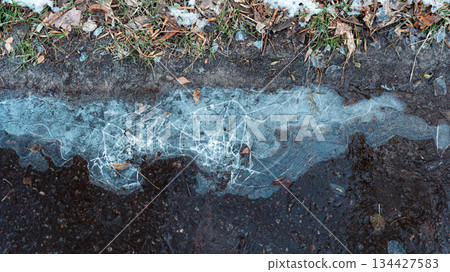 A frozen puddle with intricate ice patterns 134427583