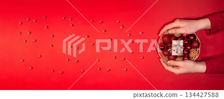 Christmas Basket with Red Baubles and Gift on Red Background 134427588