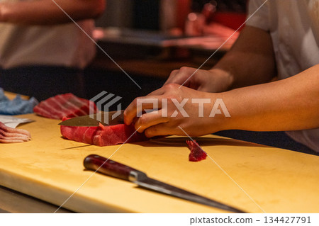 Skilled chef preparing fresh sushi with vibrant ingredients on wooden board 134427791