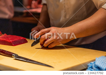 Chef slicing fresh fish on wooden cutting board in professional kitchen Chef slicing fresh fish on wooden cutting board in professional kitchen 134427792