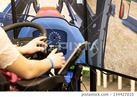 Berlin, Germany - January 24, 2025: Young woman operating tractor simulator with dual screens in training 134427810