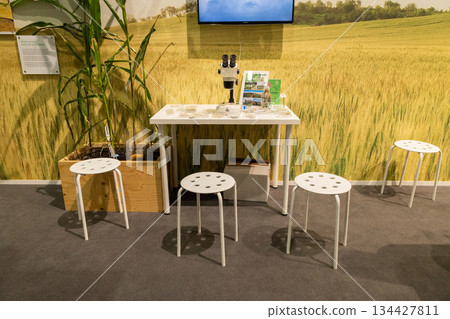 Berlin, Germany - January 24, 2025: Modern table with white stools in bright agricultural exhibition space 134427811