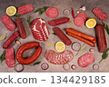 Delicious, aromatic appetizers of various salami cuts for the holidays. A selection of various smoked and dry-cured sausages and spices on a kitchen background. Advertising and menu for a store 134429185