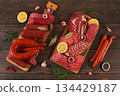 An assortment of various types of sausages, smoked meats, salami, and game sausages with lemon, spices, and herbs on a concrete table. Advertising and banner for a store, menu for a cafe or restaurant 134429187