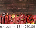 Selection of various smoked and dry-cured sausages, sliced salami, and spices on a kitchen counter. Advertising and menu for a store, banner for a cafe or restaurant. Delicious holiday appetizers, 134429189