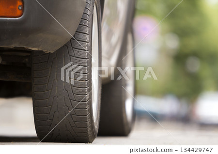 Detail of car, wheels with aluminum discs and new black rubber tire protector on light blurred background. Transportation, safety, reliability, modern design concept. Detail of car, wheels with aluminum discs and new black rubber tire protector on light blurred background. Transportation, safety, reliability, modern design concept. 134429747