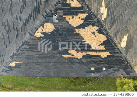 Consequences of natural disaster. Damaged house roof with missing shingles after hurricane Ian in Florida 134429800
