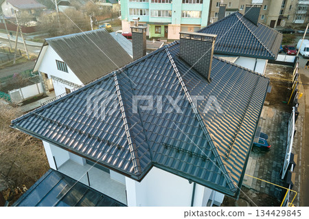 Closeup of house roof top covered with ceramic shingles. Tiled covering of building Closeup of house roof top covered with ceramic shingles. Tiled covering of building 134429845