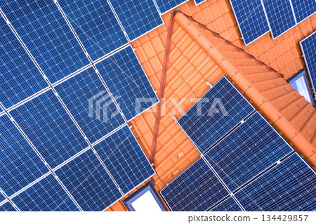 Close-up surface of blue shiny solar photo voltaic panels system on building roof. Renewable ecological green energy production concept. Close-up surface of blue shiny solar photo voltaic panels system on building roof. Renewable ecological green energy production concept. 134429857