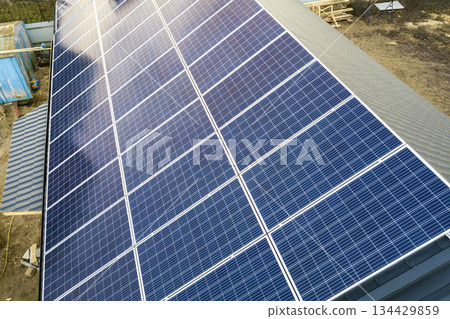 Close-up surface of blue shiny solar photo voltaic panels system on building roof. Renewable ecological green energy production concept. Close-up surface of blue shiny solar photo voltaic panels system on building roof. Renewable ecological green energy production concept. 134429859