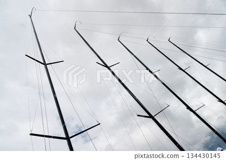 Few masts of sailboats moored in yacht club, ropes and aluminum, cloudy weather 134430145