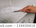 Male hand using knife to scraping away thick ice buildup from inside refrigerator, emphasizing routine task of maintaining clean kitchen appliance. Concept of domestic work, housekeeping. 134430418