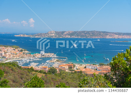 Seaside town overlooking a bright blue bay under clear sky. Coastal travel destination, summer vacation and Mediterranean atmosphere, Palau, Italy Seaside town overlooking a bright blue bay under clear sky. Coastal travel destination, summer vacation and Mediterranean atmosphere, Palau, Italy 134430887