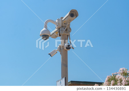 Street security camera mounted on a pole against clear blue sky. Urban surveillance, public safety and modern city infrastructure concept Street security camera mounted on a pole against clear blue sky. Urban surveillance, public safety and modern city infrastructure concept 134430891